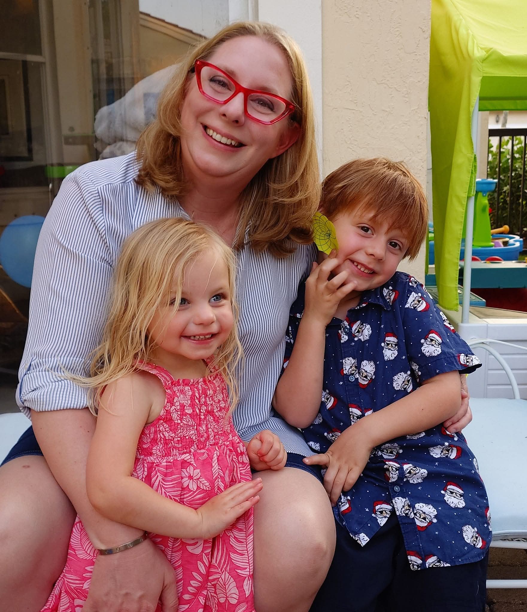 Lauren smiling with her two children outside on a bench